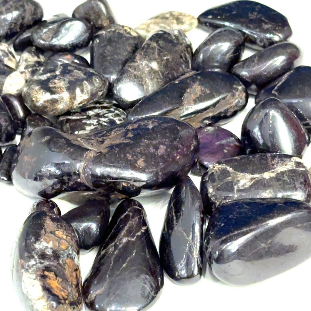 Multiple Purpurite tumbled stones arranged on white background showing variations on white background overview