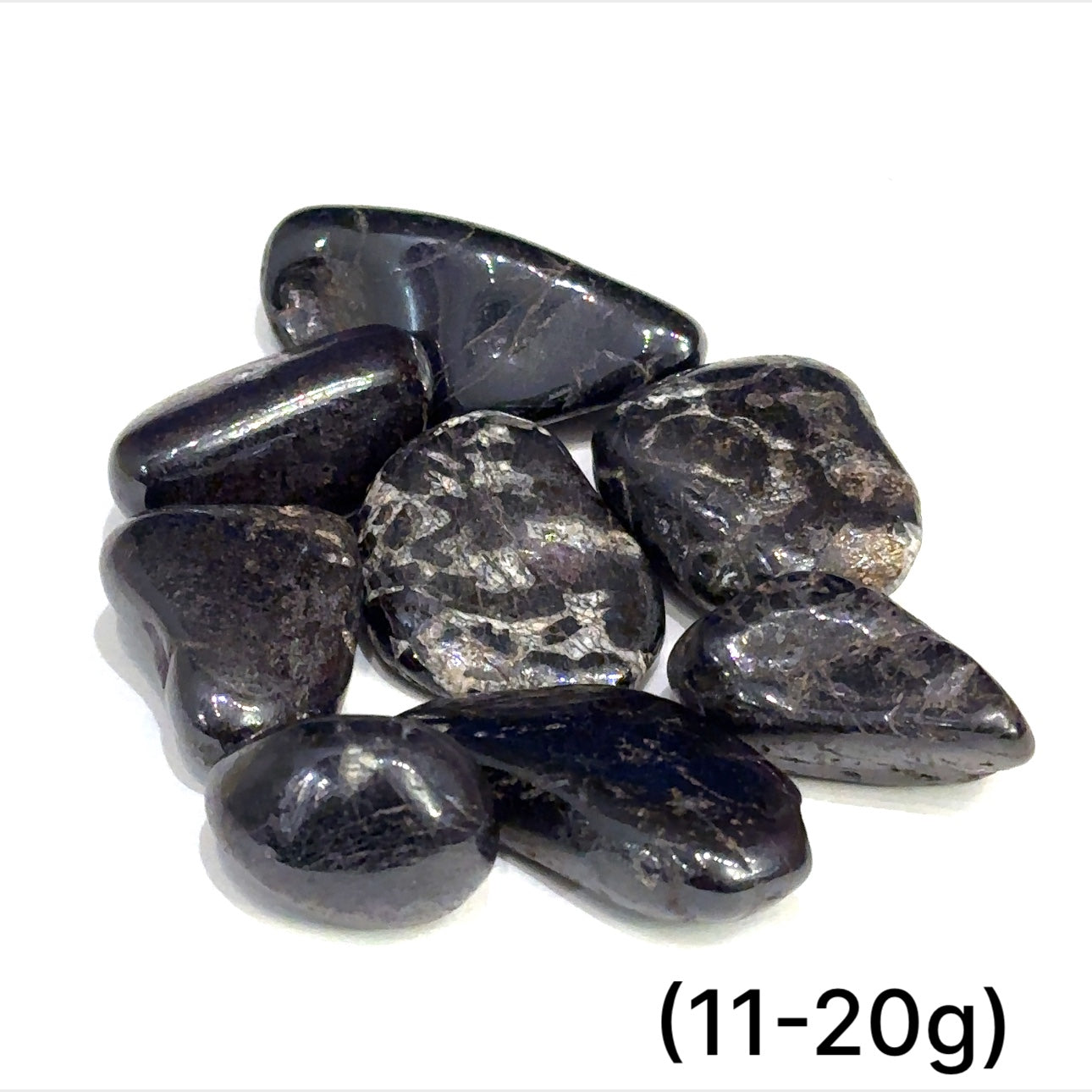 Multiple Purpurite tumbled stones arranged on white background showing variations sizes (11-20g) on white background overview