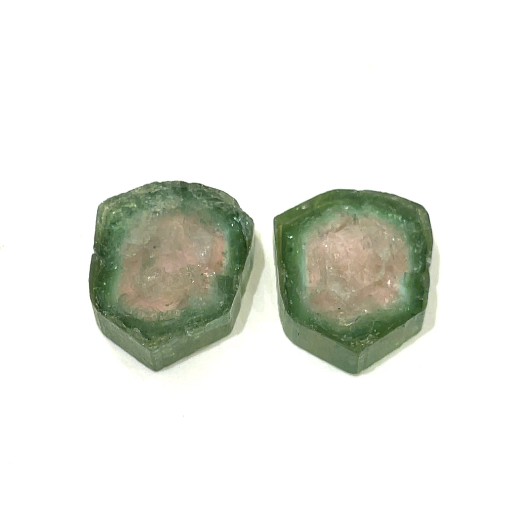 Multiple Watermelon Tourmaline gemstones are displayed together, showing natural variation. On white background laying flat front center view