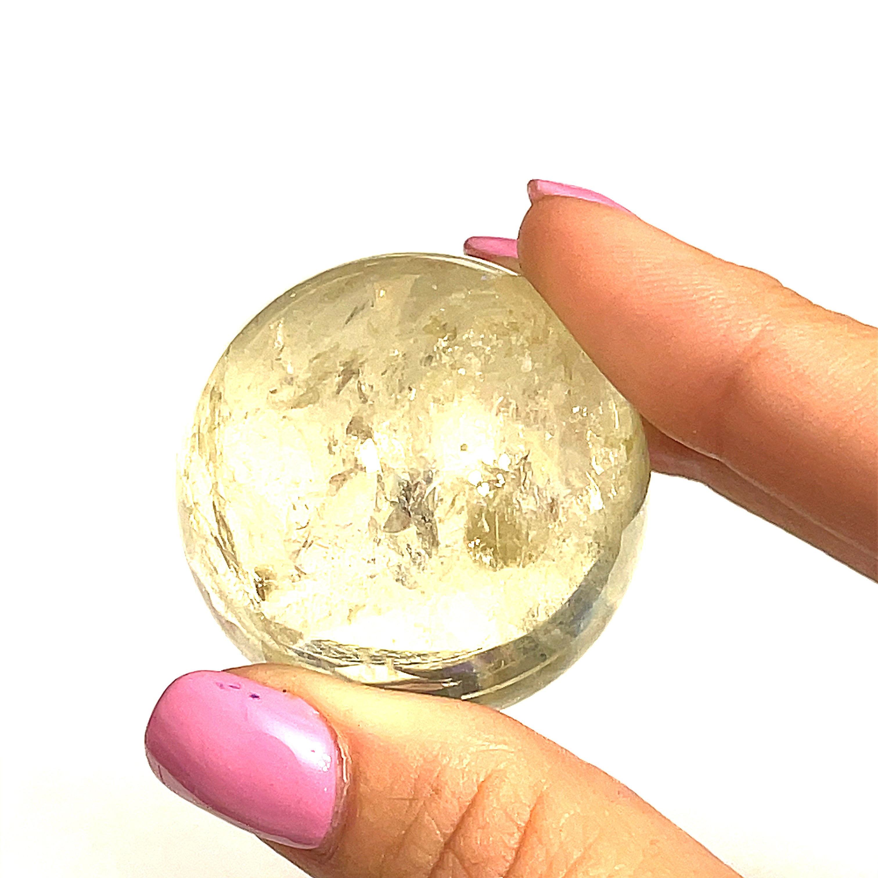 One citrine gemstone sphere held by a model on a white background for a close up overview.