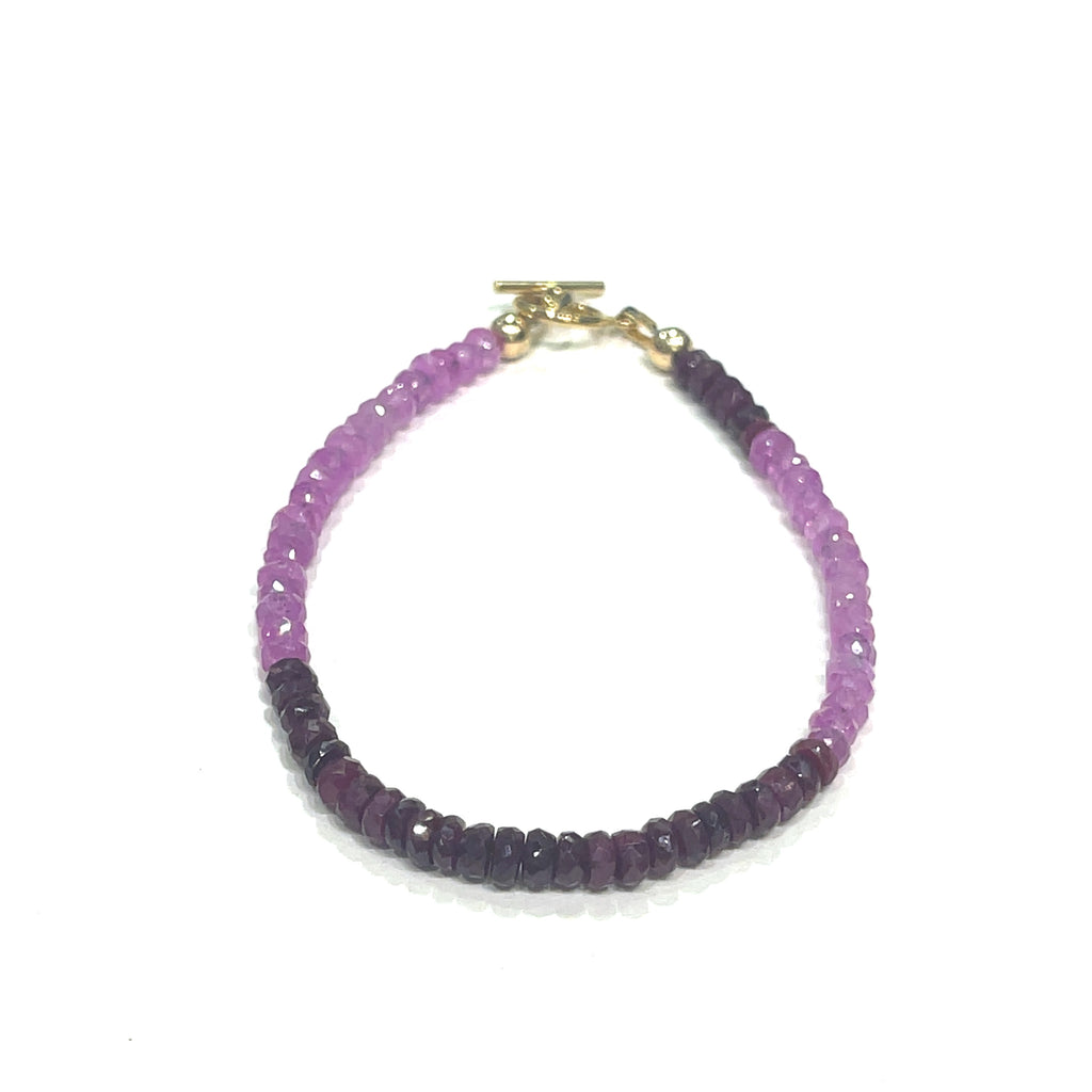 One genuine ruby gemstone beaded bracelet with gold-filled toggle clasps, featuring faceted round rubies ranging from pink to red on a white background, front overview.