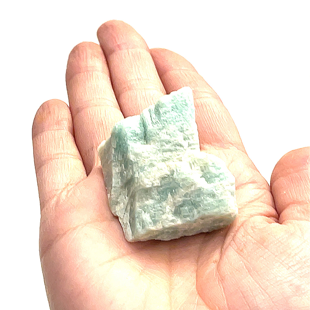 One raw Amazonite gemstones is displayed in a models palm on a white background, in front, in an overview. 