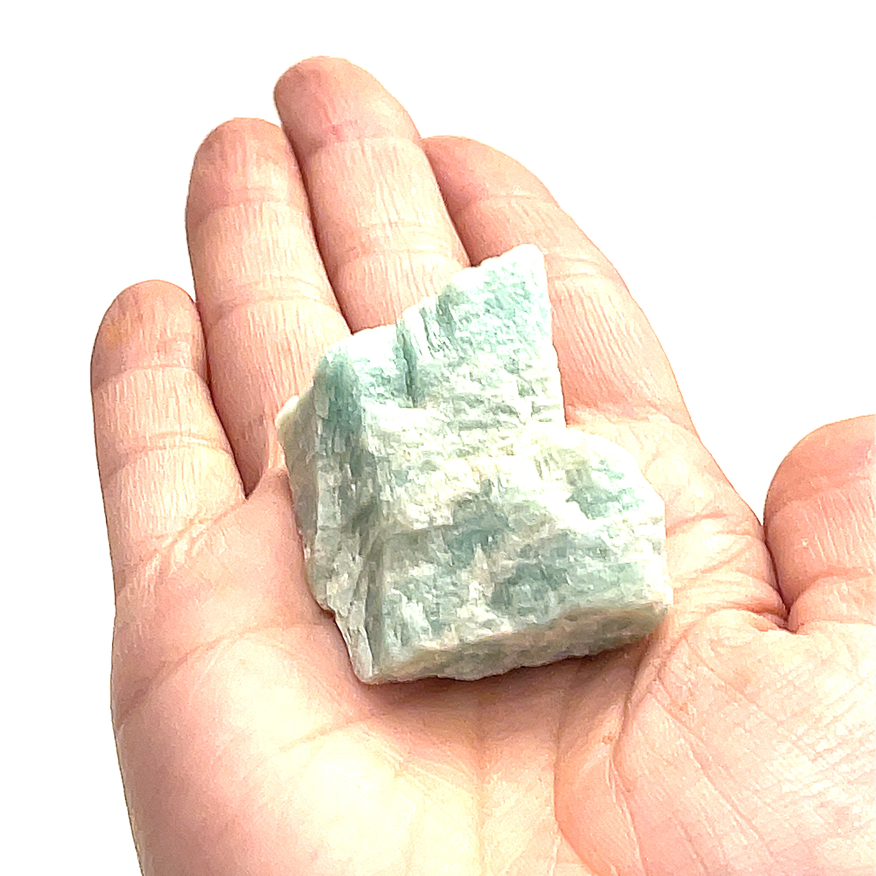 One raw Amazonite gemstones is displayed in a models palm on a white background, in front, in an overview. 