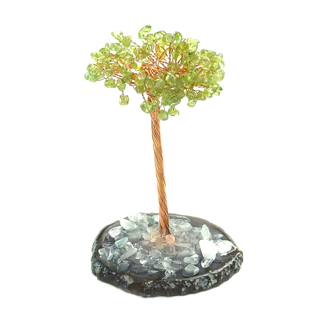 Peridot Gemstone tree placed on an altar for home décor and energy healing. On a white background, front view.