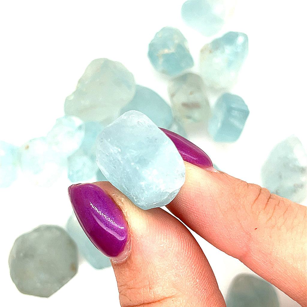 Raw Blue Topaz Gemstone on white grouping center  closeup overview in finger tips
