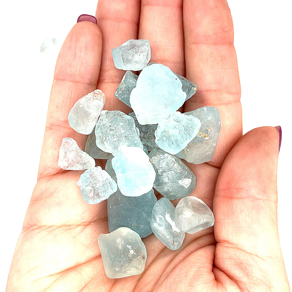 Raw Blue Topaz Gemstone on white grouping center up close front view in hand