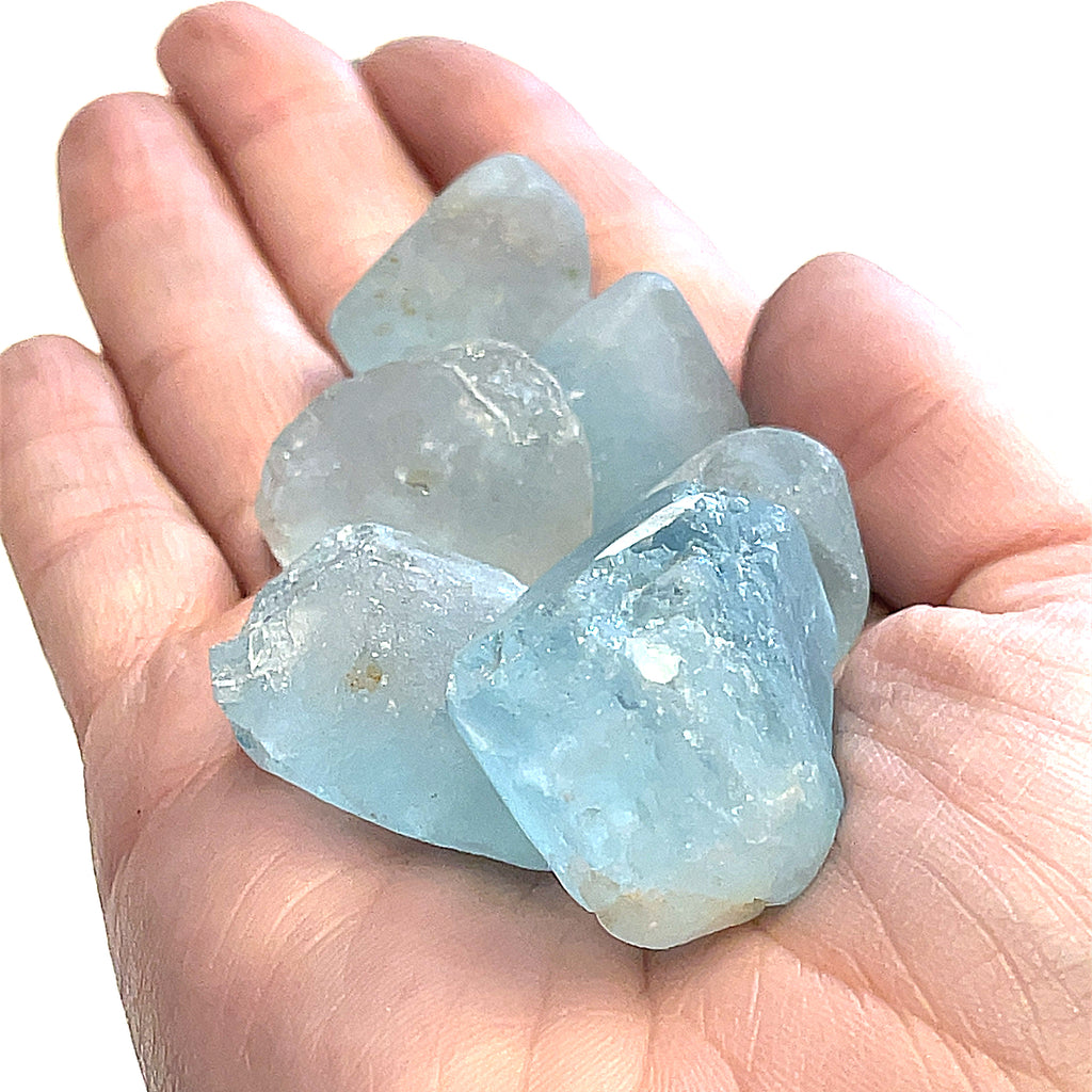 Raw Blue Topaz Gemstone on white grouping extra large center  overview in palm of hand