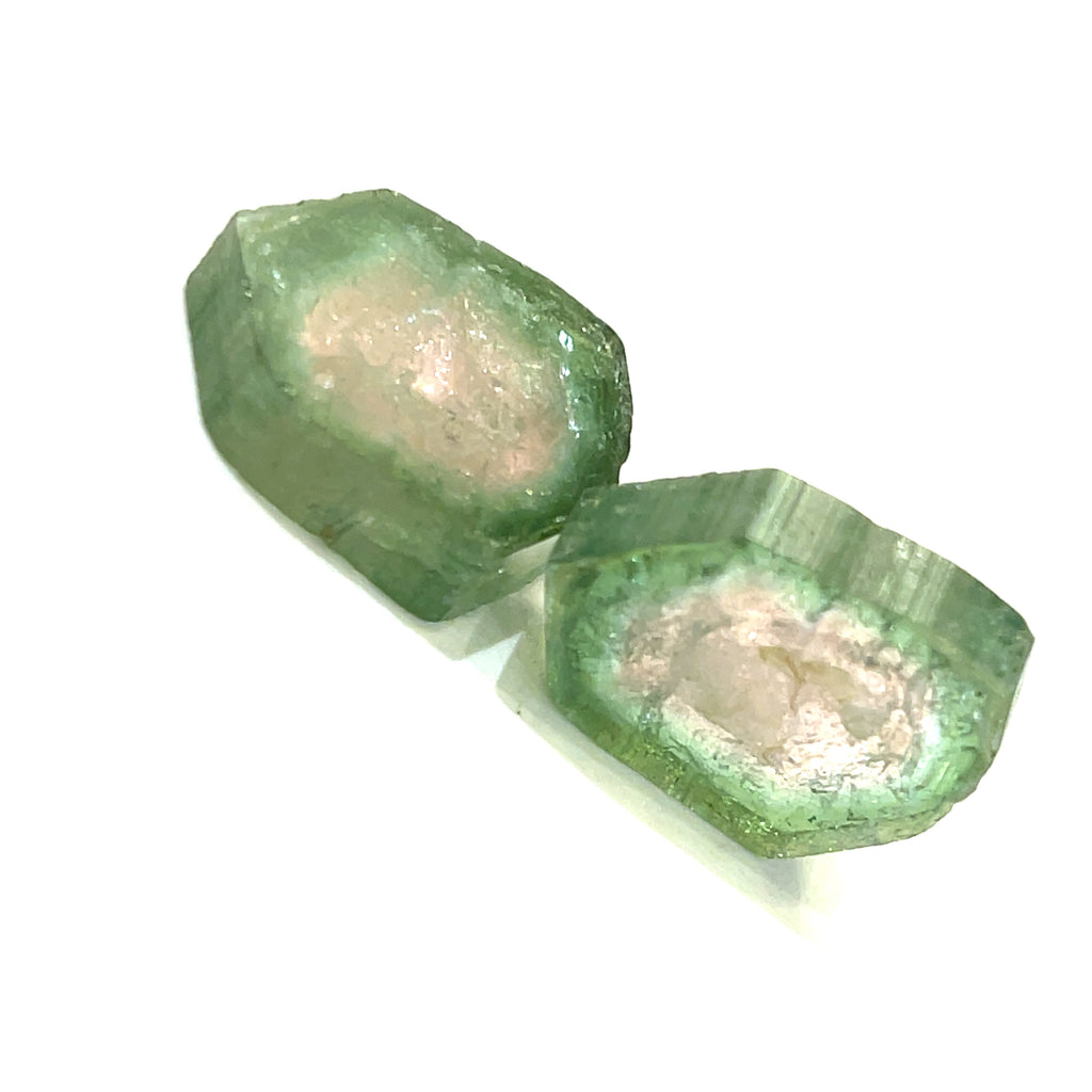 Raw Watermelon Tourmaline gemstone showing pink and green layers on white background diagonal overview.