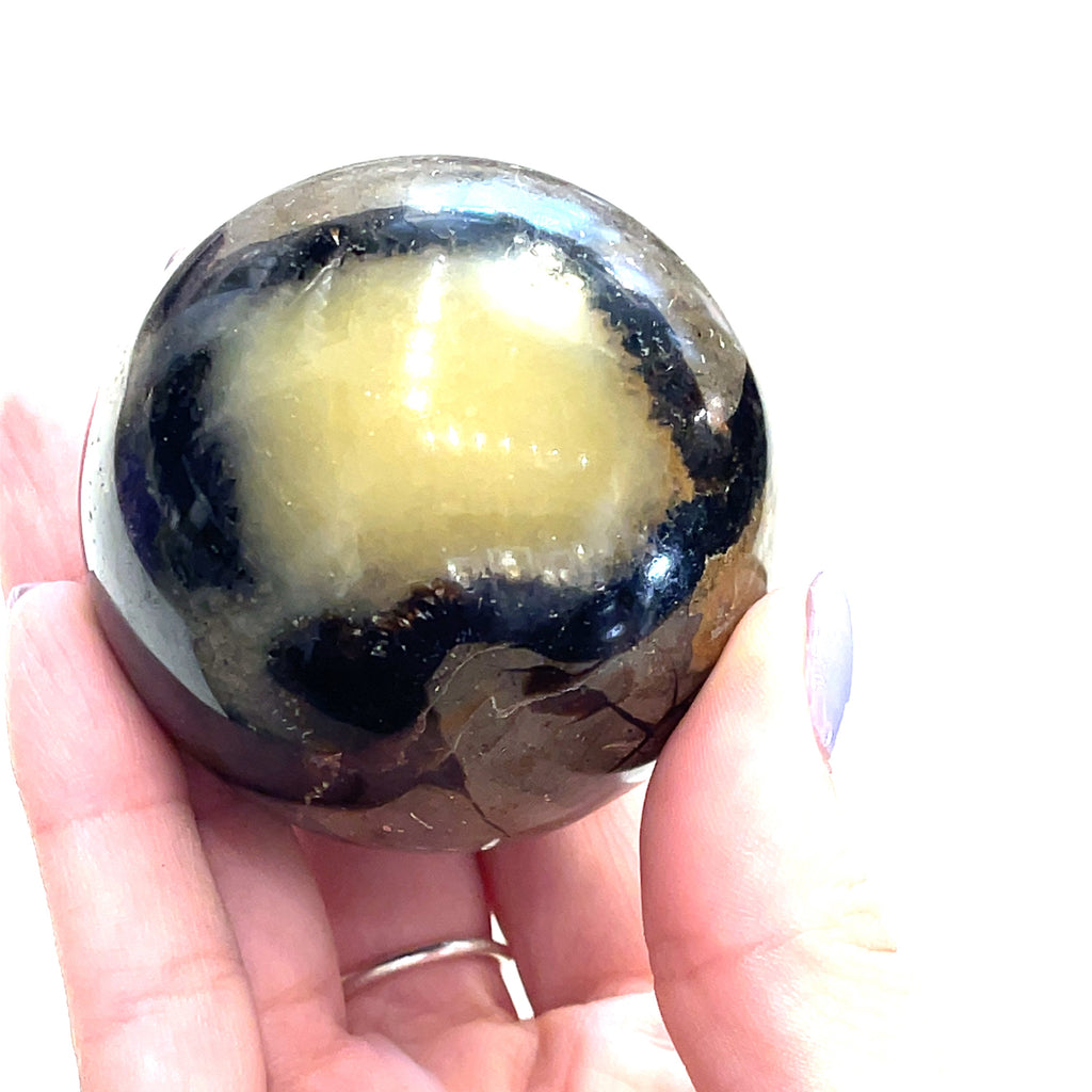 Septarian Nodule palm stone showing natural calcite and aragonite pattern in a models finger tips front view. 
