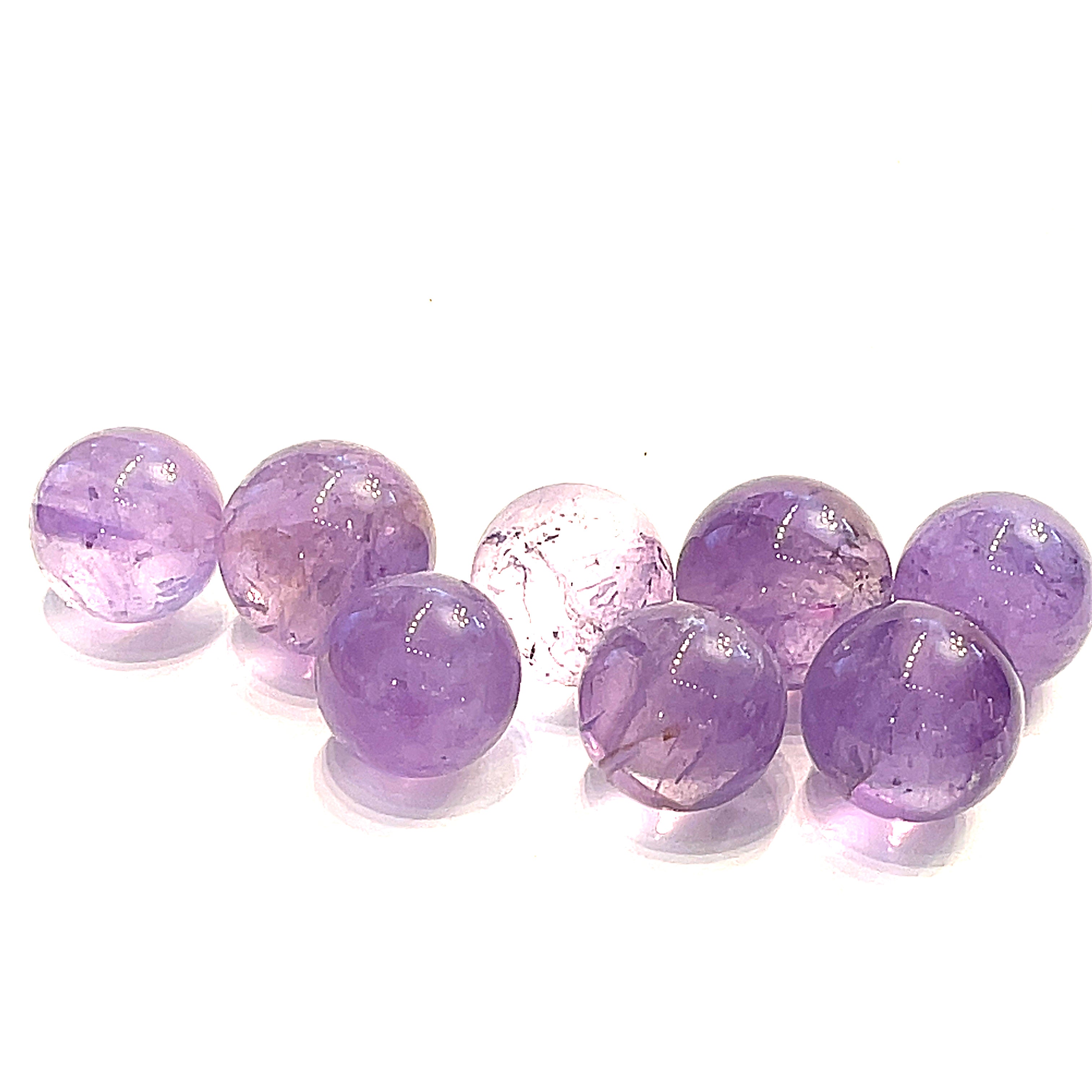  Several small purple amethyst gemstone spheres on a white background, front, center, close-up overview. 