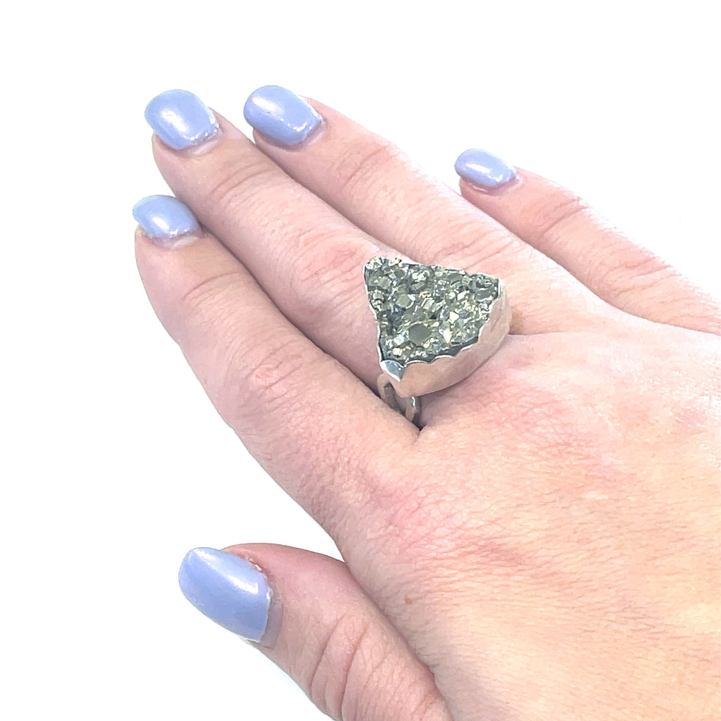 Statement Pyrite ring in scalloped bezel setting — handmade gemstone jewelry on a models finger on a white background front overview. 
