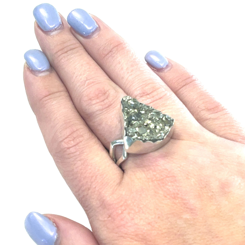 Statement Pyrite ring in scalloped bezel setting — handmade gemstone jewelry on a models finger on a white background front slight left angle overview. 
