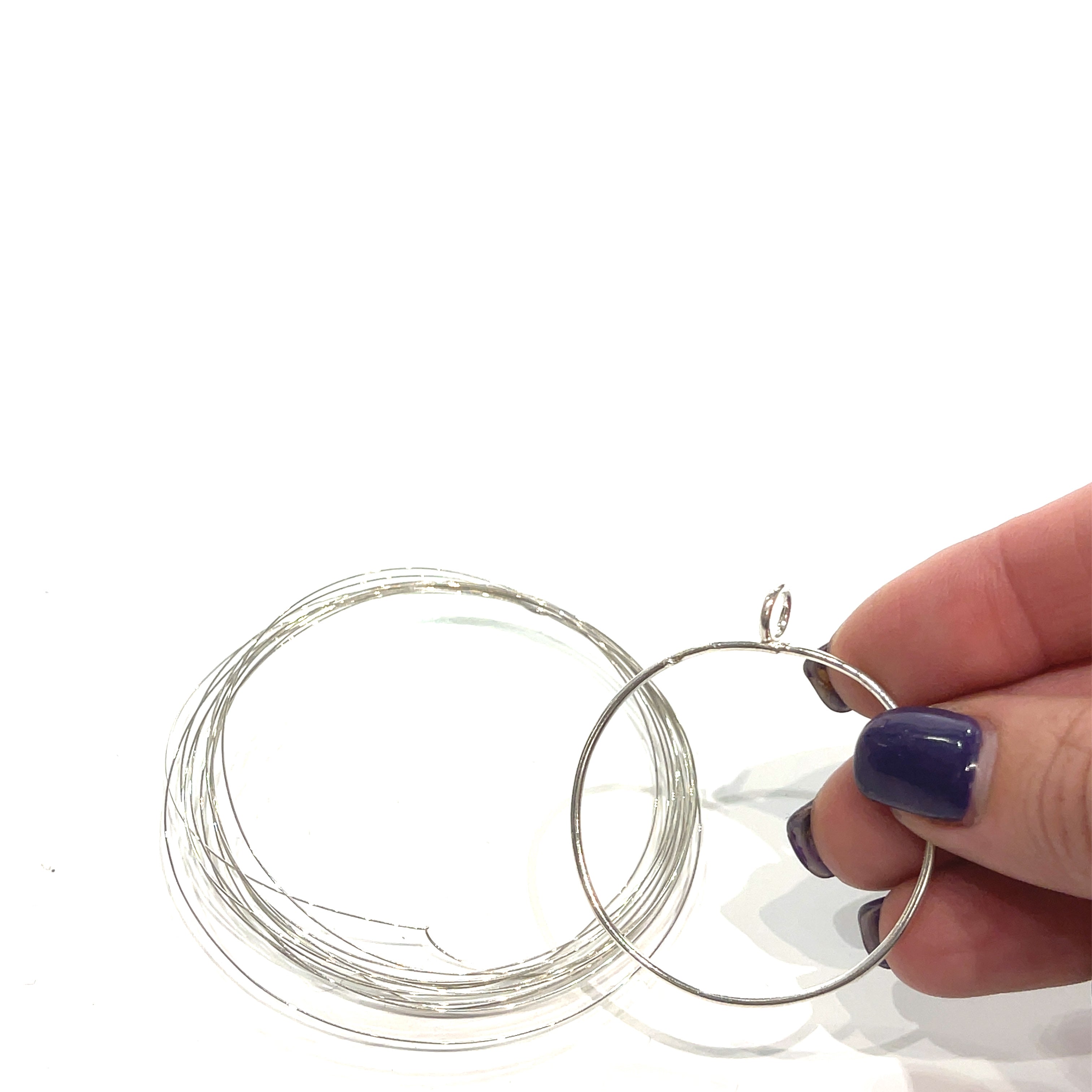 Sterling Silver Wire and the pendant outline in a model's hand on a white background, front view. 
