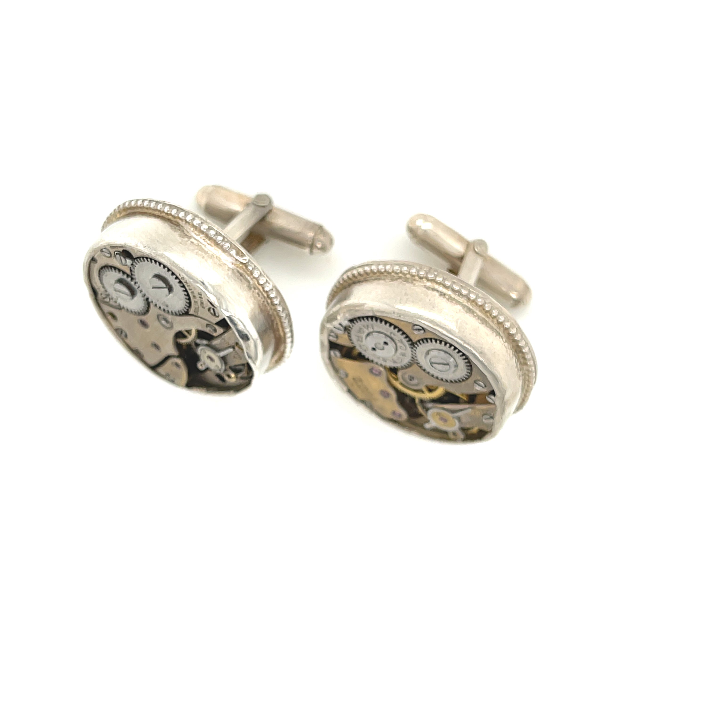Sterling silver cuff links with mechanical detail handcrafted  in Boston on a white background  a close up center top view.