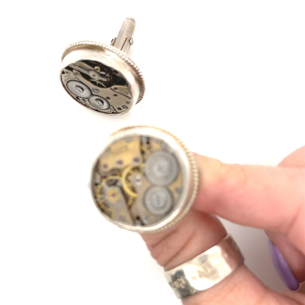 Sterling silver cuff links with mechanical detail handcrafted  in Boston on a white background in a models finger tips for a close up view. 