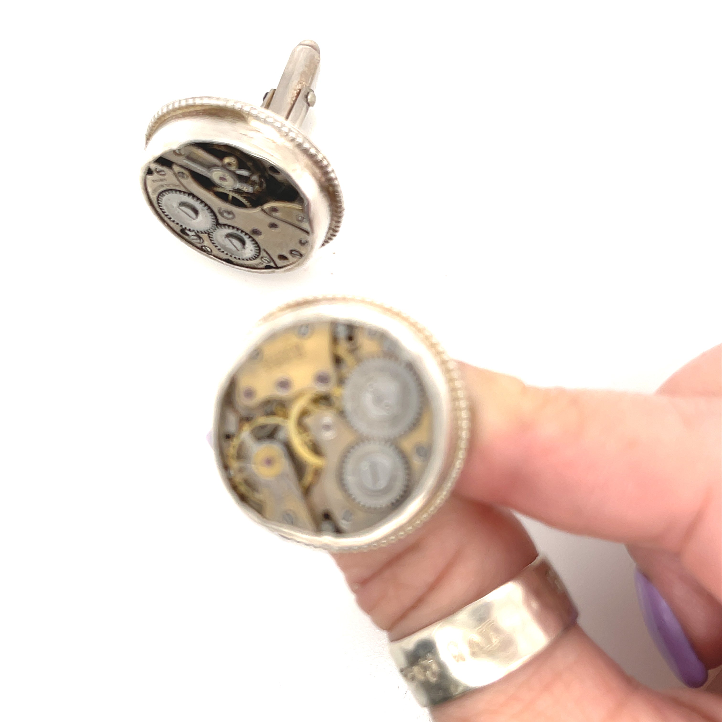 Sterling silver cuff links with mechanical detail handcrafted  in Boston on a white background in a models finger tips for a close up view. 