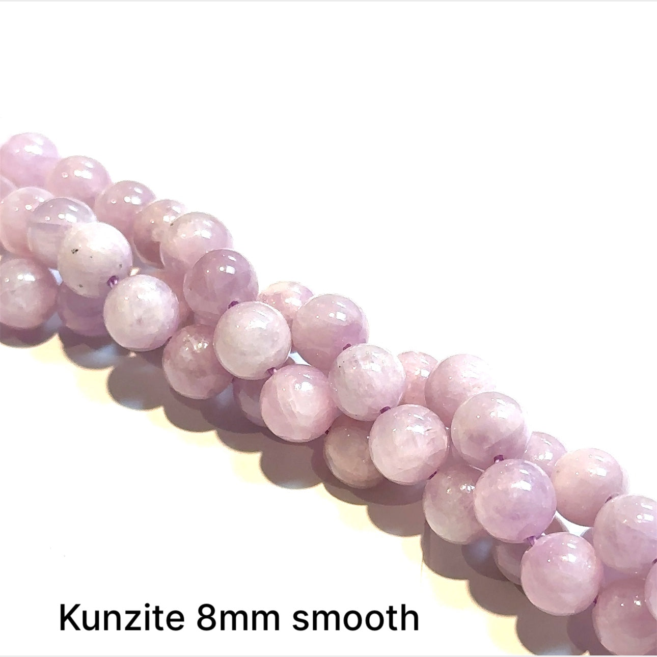 Strand of Kunzite 8mm smooth rounde on a white background, front view.