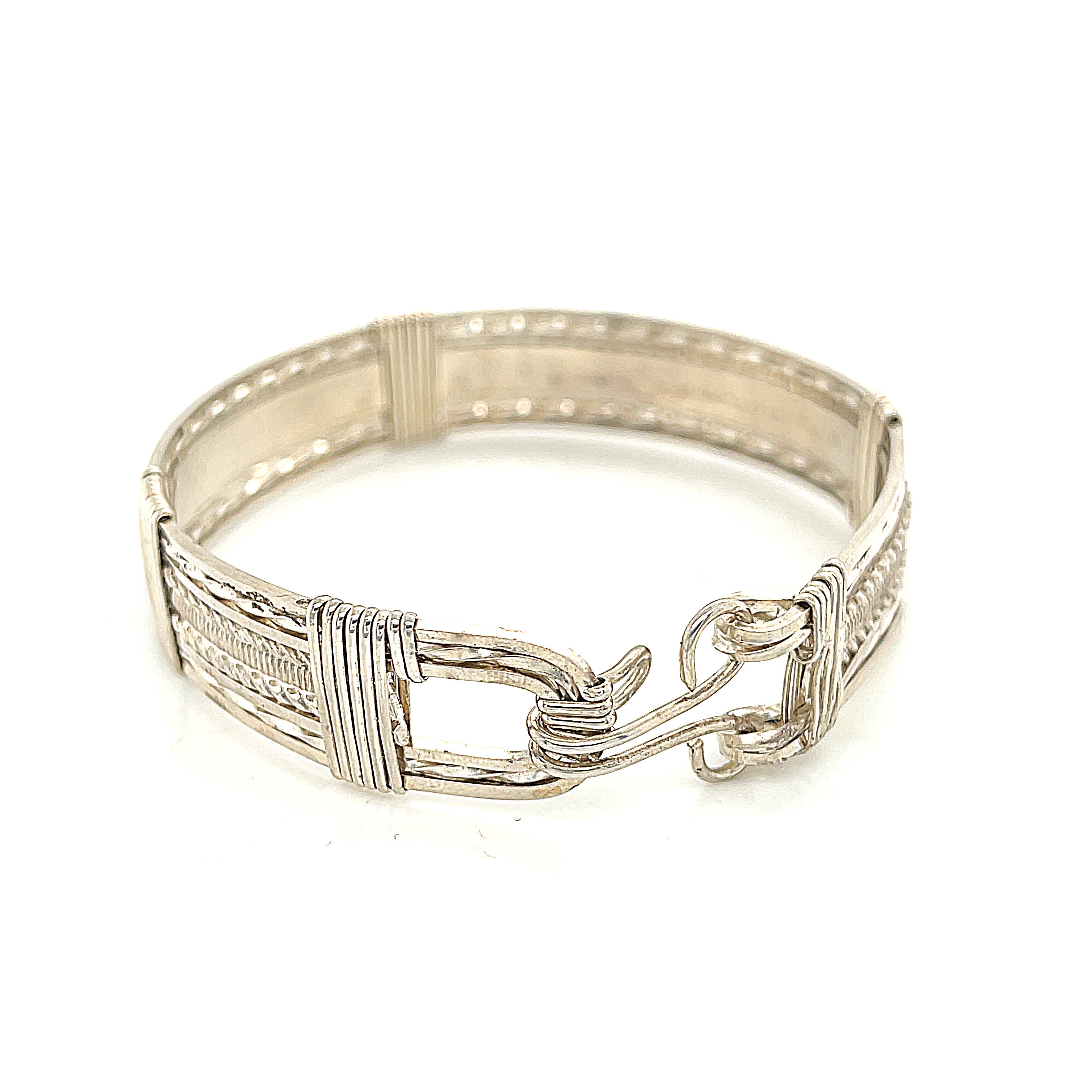Style #1 Handcrafted sterling silver wire-wrapped bangle with twisted and straight wire combination showing polished dome centerpiece, on a white background, close up  back view. 