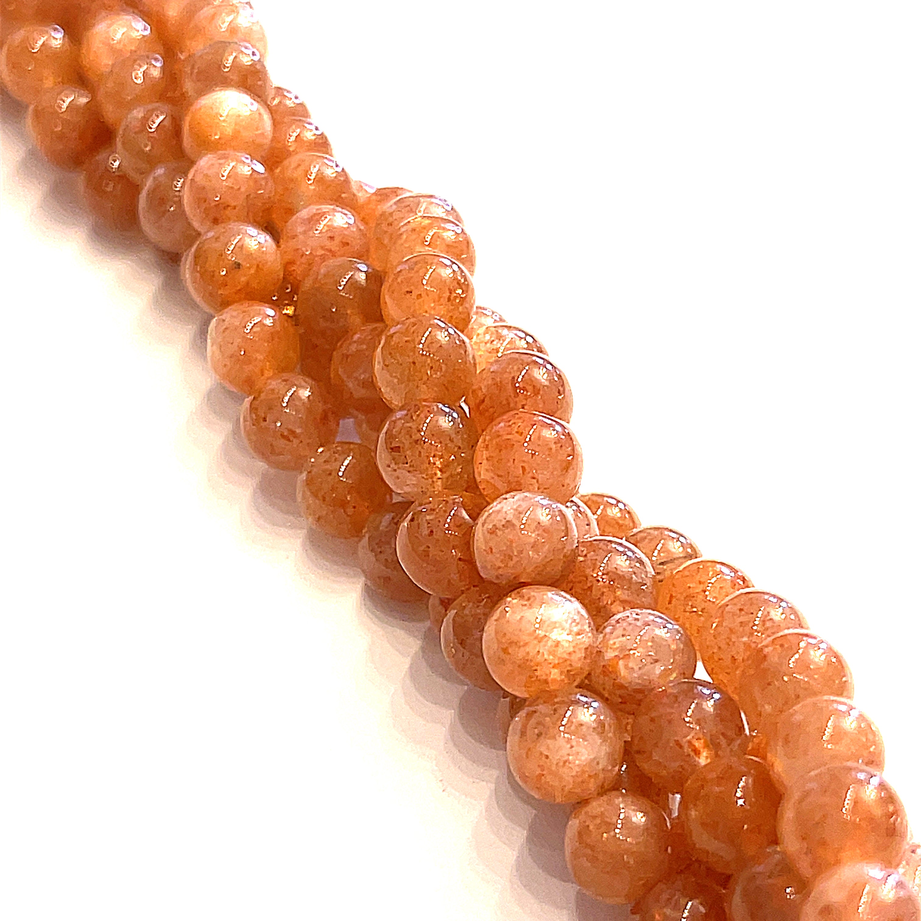 Sunstone 6mm smooth round gemstone strand on a white background, overview. 
