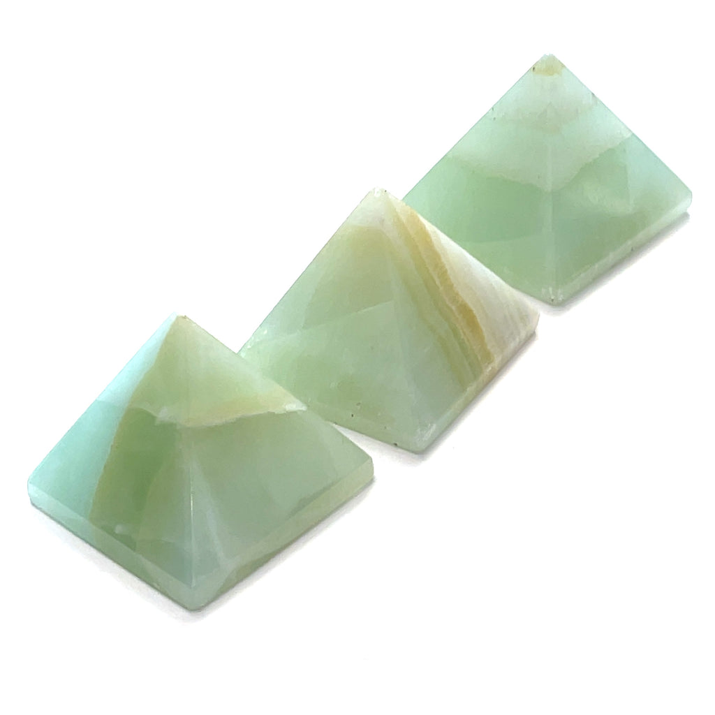 Three green calcite gemstone pyramids arranged diagonally on a white background front overview.