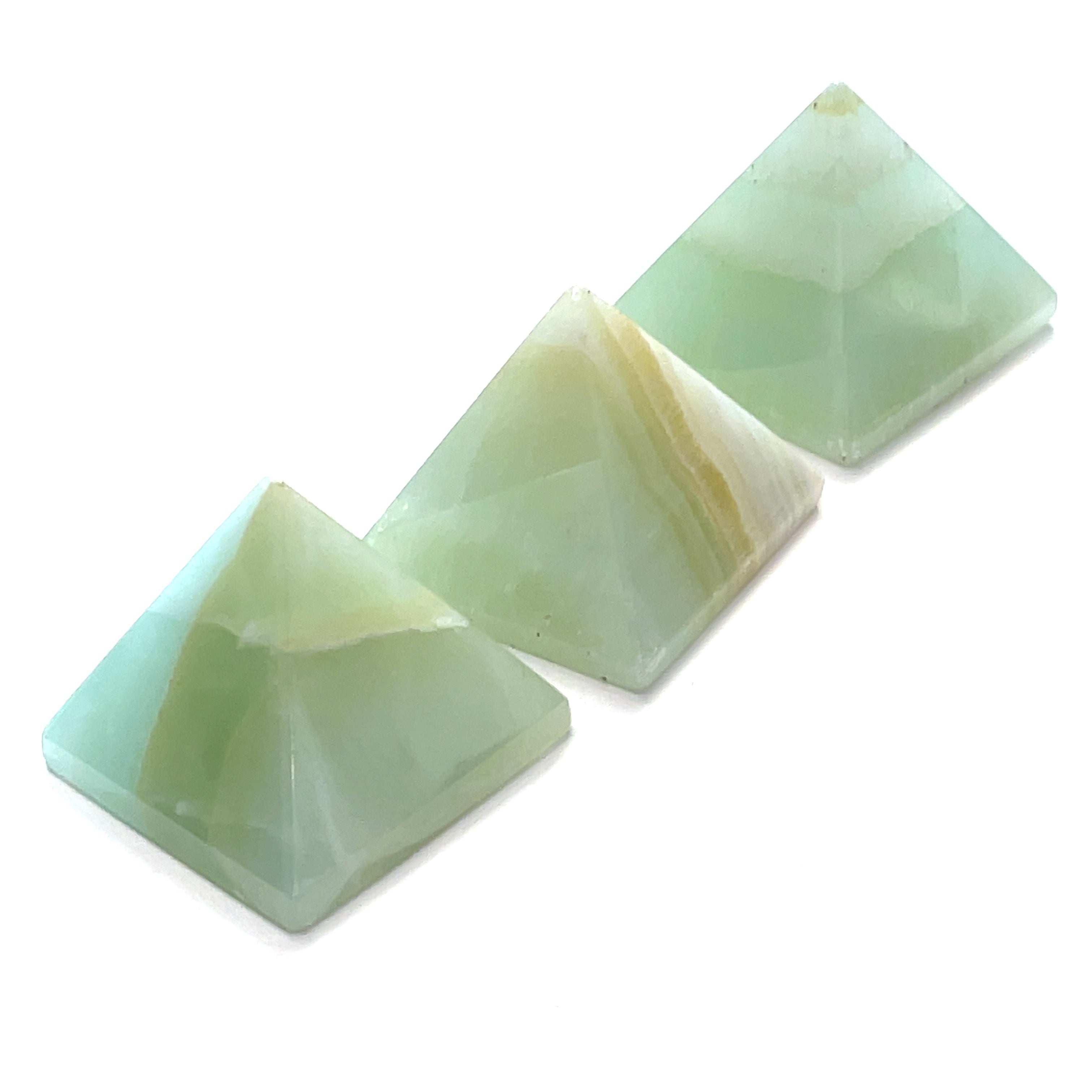 Three green calcite gemstone pyramids arranged diagonally on a white background front overview.