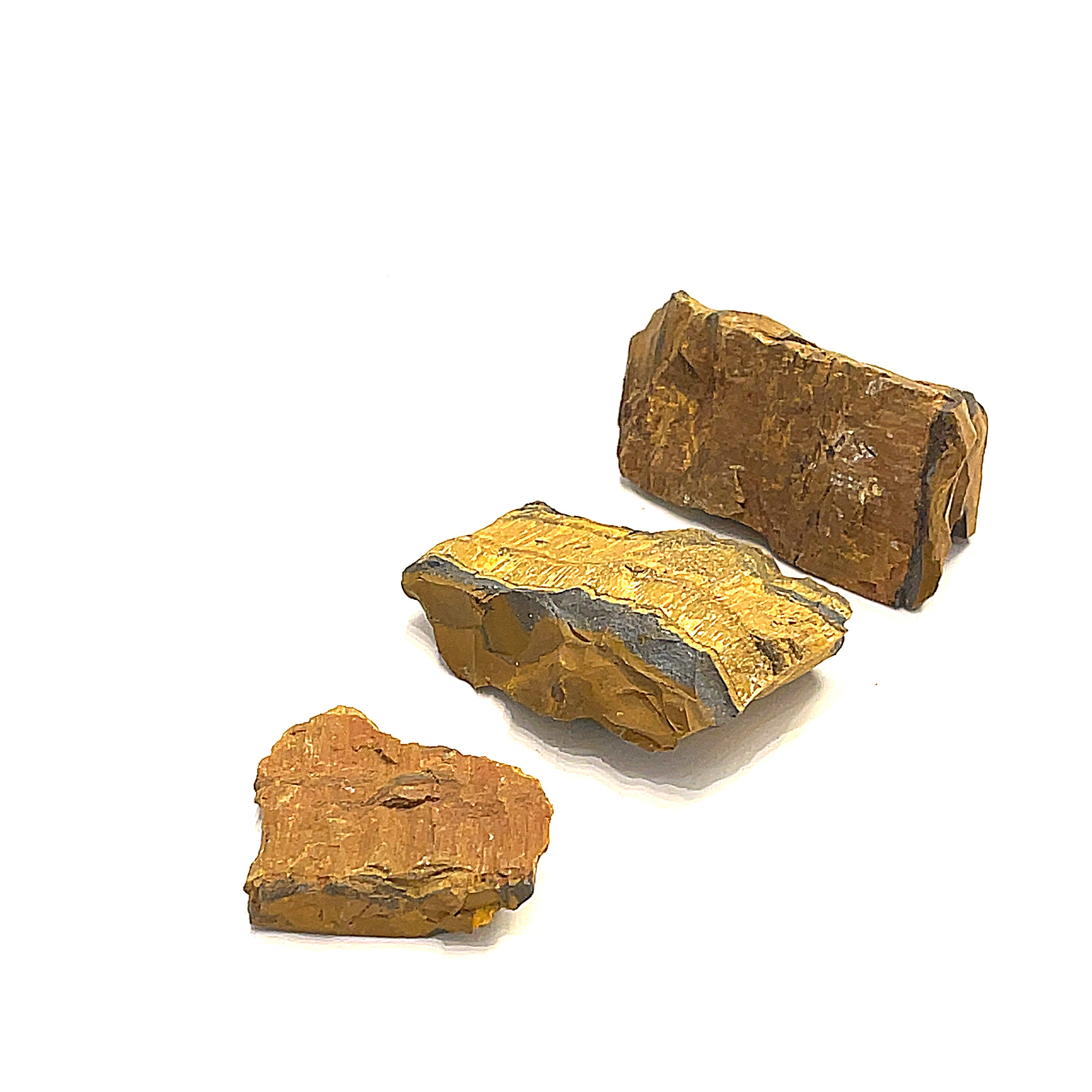 Three pieces of raw golden tiger eye gemstones are displayed on a white background, in a front overview. 