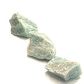 Three raw Amazonite gemstones are displayed on a white background, in front, in an overview. 