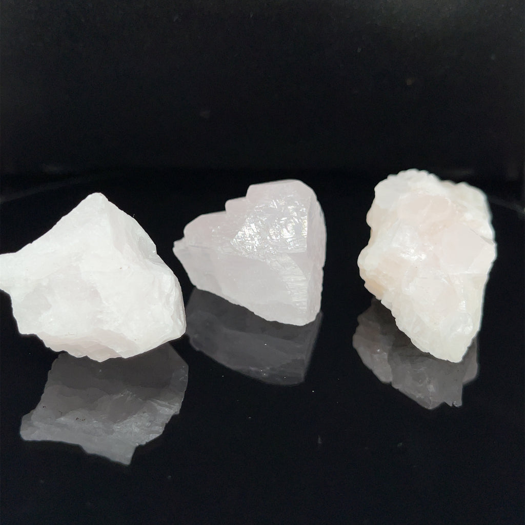 Three raw mangano calcite (6-11g) on a black background, front view. 