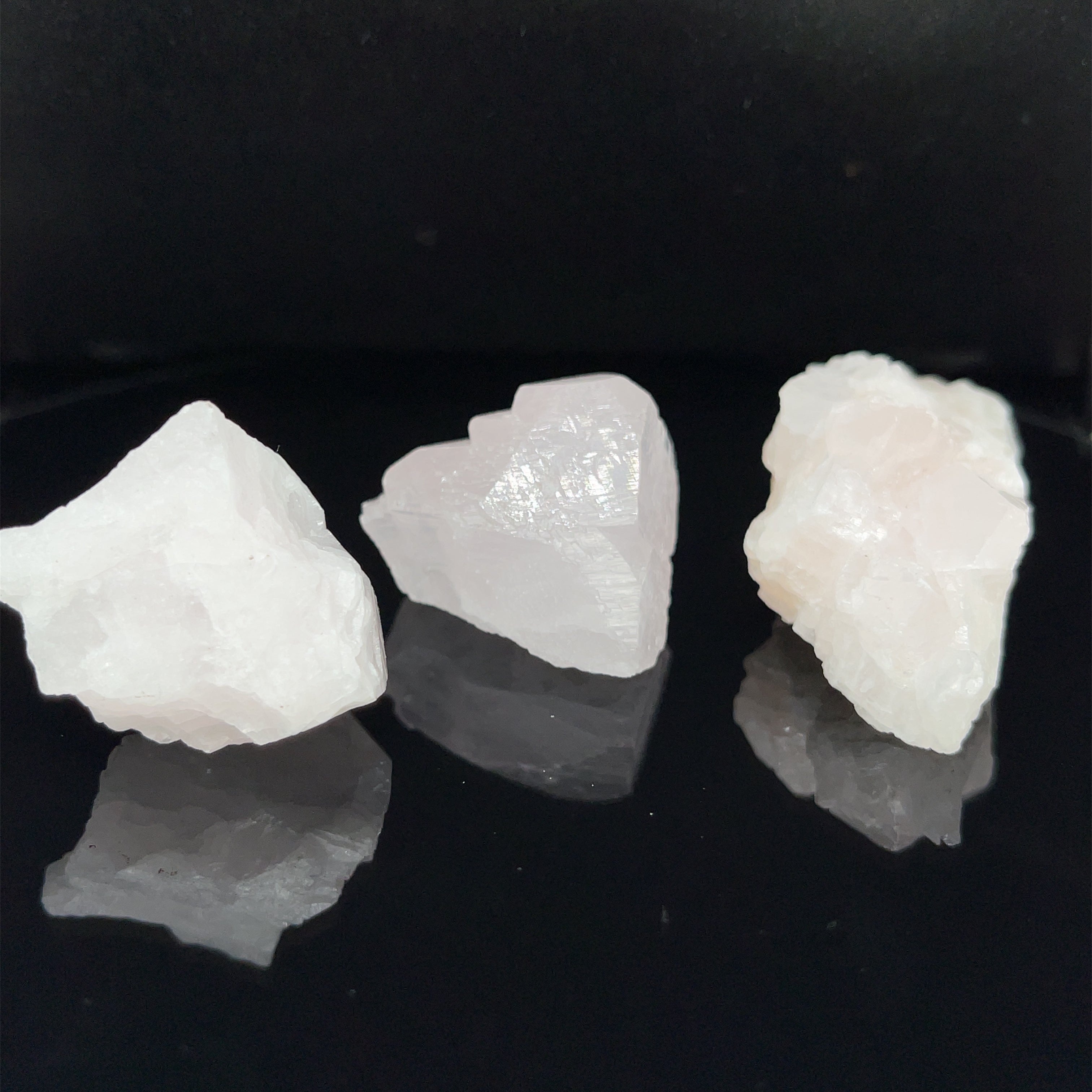 Three raw mangano calcite (6-11g) on a black background, front view. 