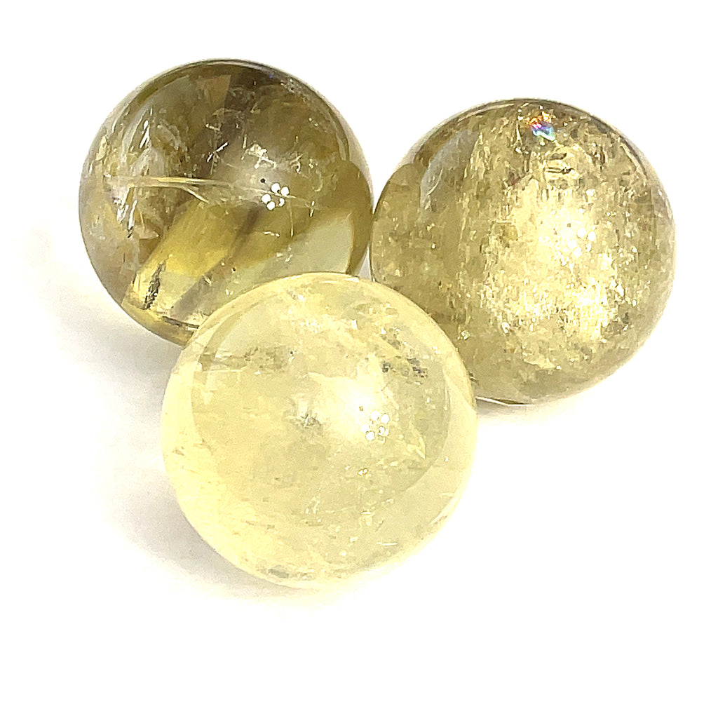 Three yellowish transparent citrine gemstone spheres of varying sizes are arranged together on a white background in the front overview.