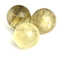 Three yellowish transparent citrine gemstone spheres of varying sizes are arranged together on a white background in the front overview.