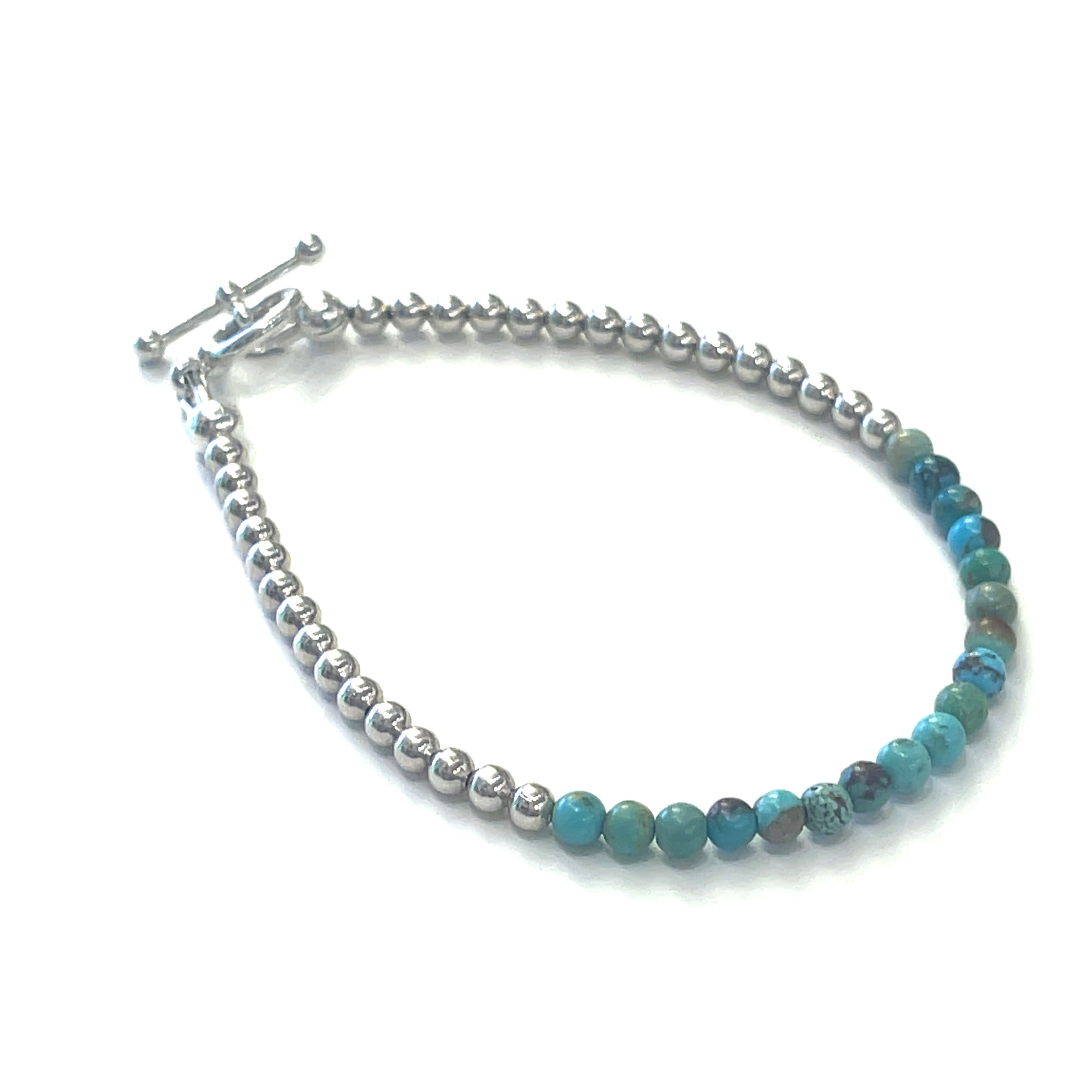 Top-grade Turquoise 3mm gemstone smooth beads strung on durable Beadalon wire with a sterling silver beads and toggle on a white background  front angel view.