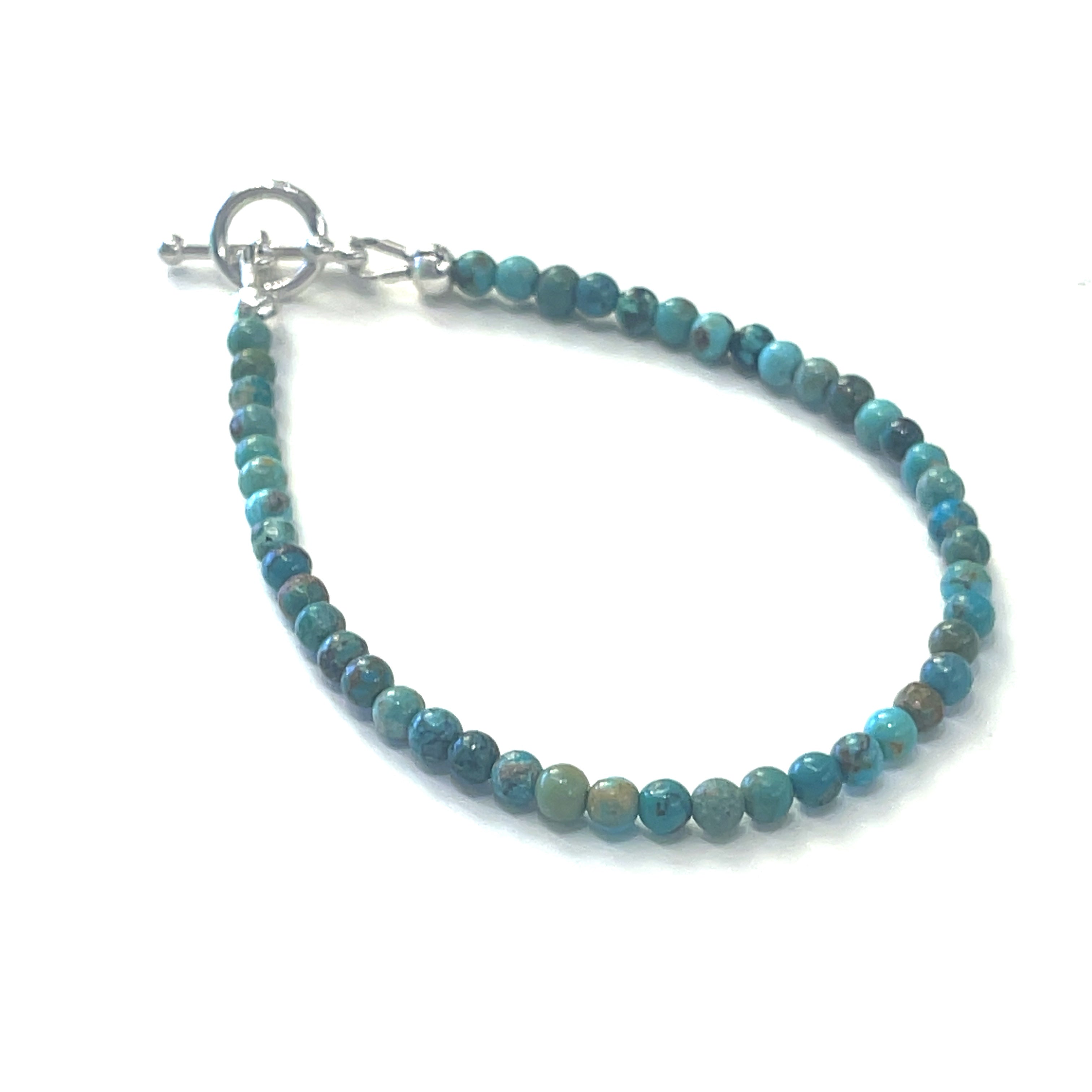 Top-grade Turquoise 3mm gemstone smooth beads strung on durable Beadalon wire with a sterling silver toggle on a white background  front angel view.