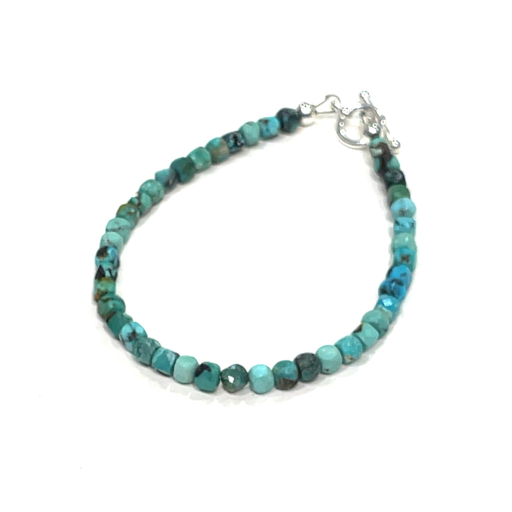 Top-grade Turquoise faceted cubed  beads strung on durable Beadalon wire with a sterling silver toggle on a white background  front right angle view. 