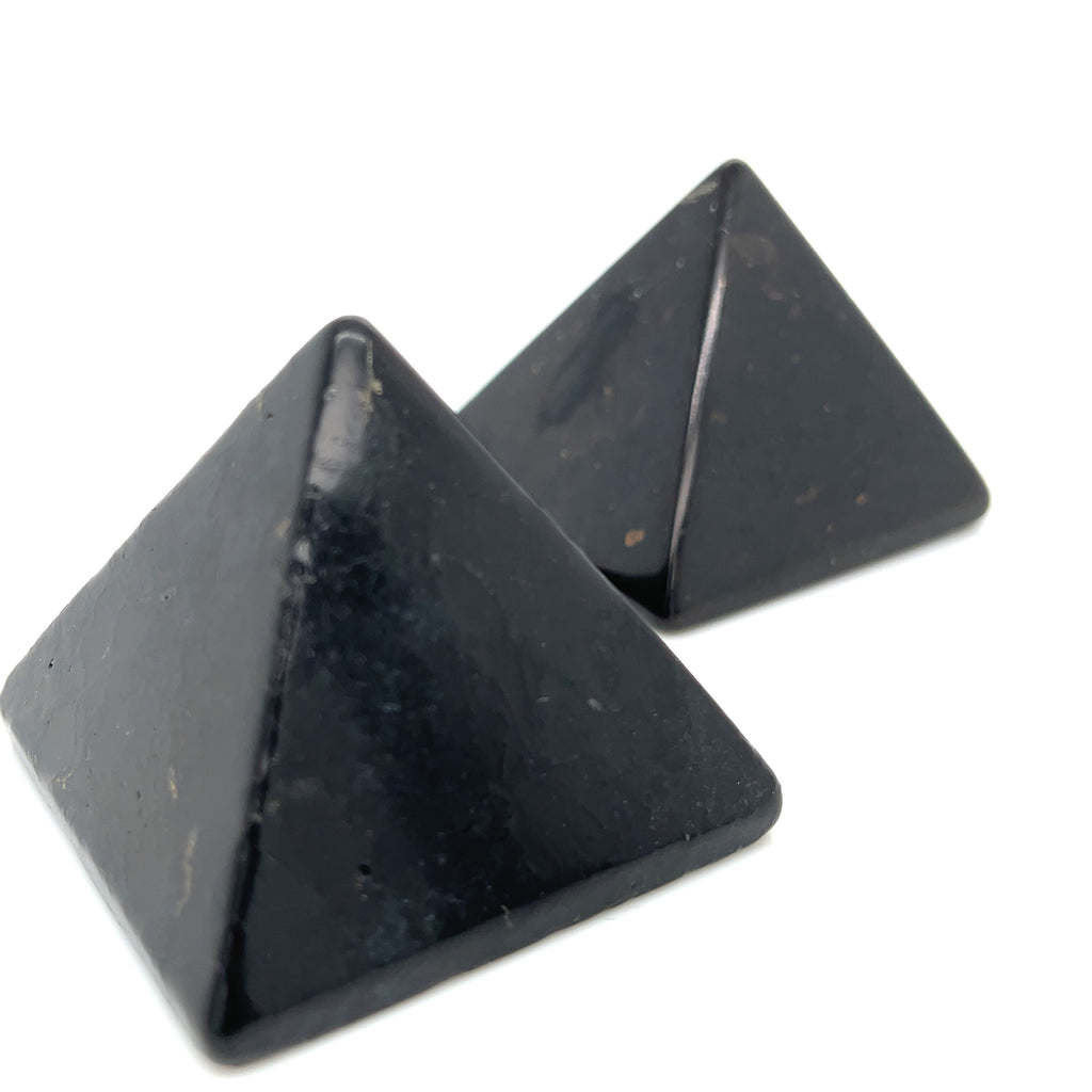 Two Black shungite pyramid for EMF protection and electromagnetic shielding on a white background, front view. 