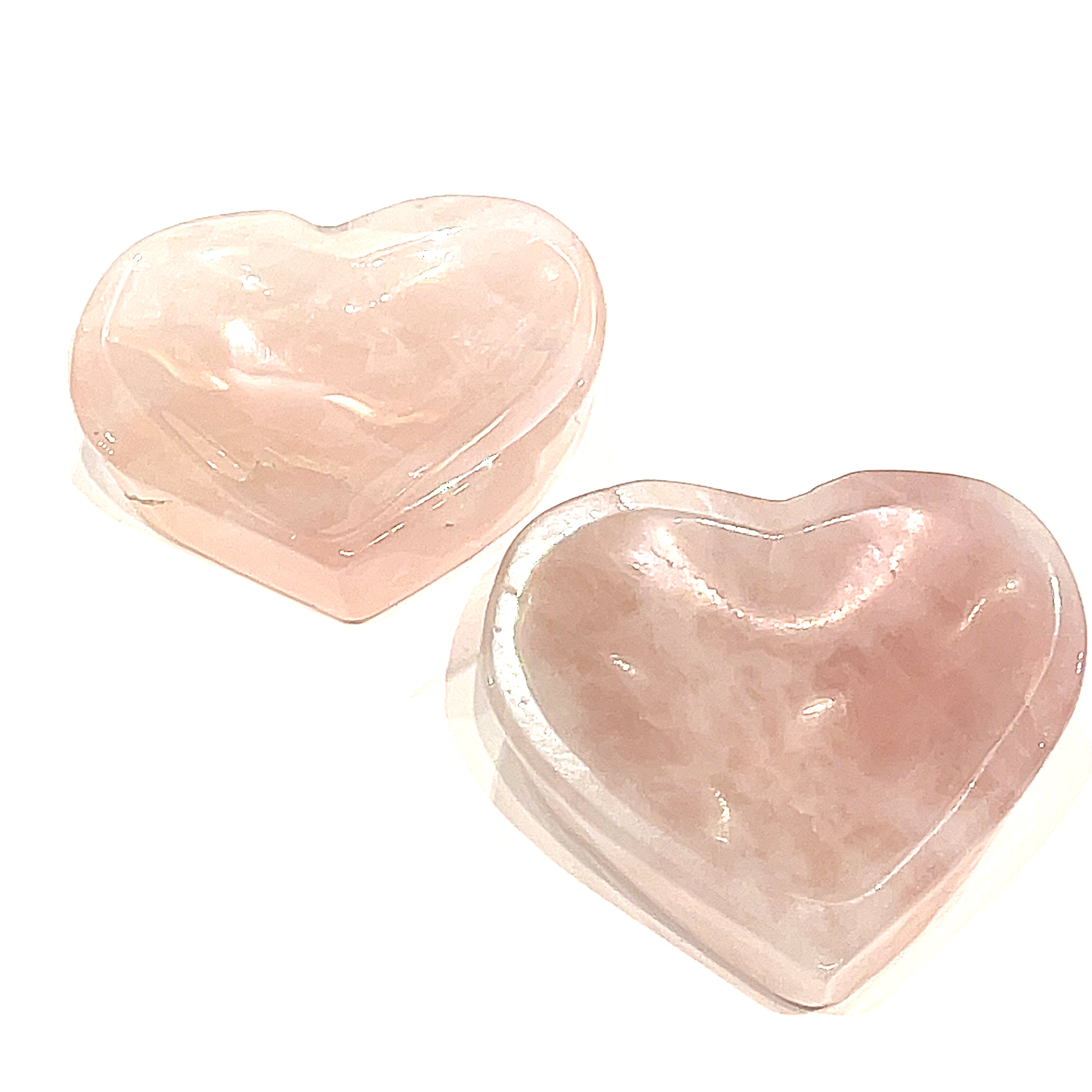 Two heart-shaped Rose Quartz gemstone bowls, one pink and one more translucent, are placed side by side, front overview on a white background. 