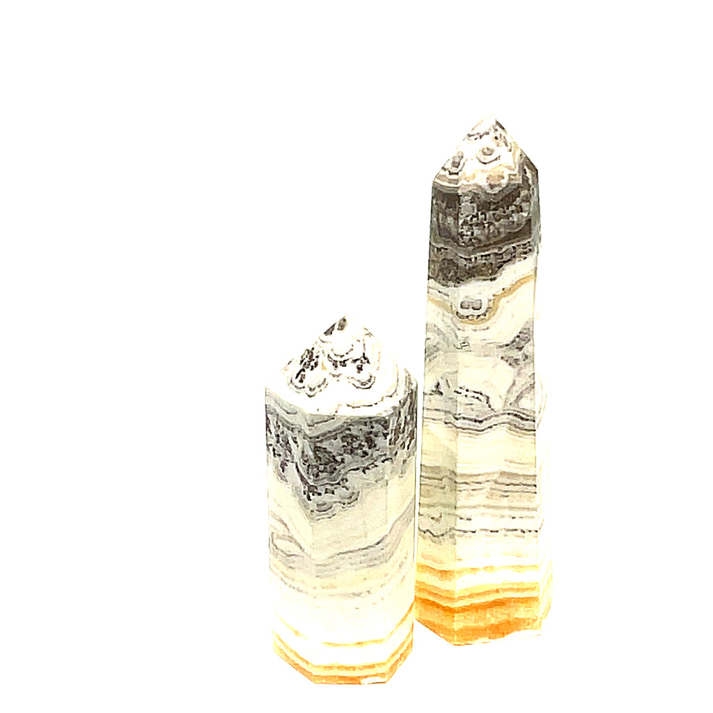 Two yellow calcite gemstone towers with black dendritic patterns against a white background, front view. 