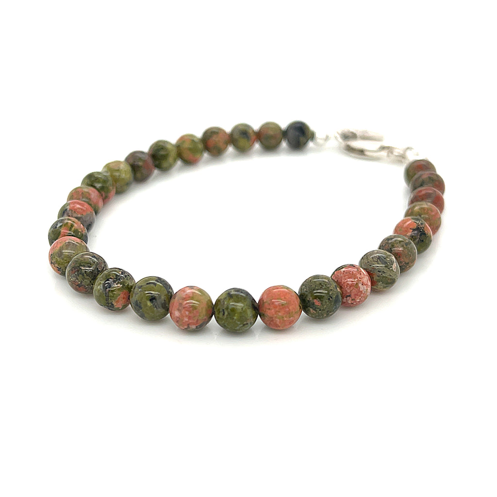 Unakite beaded bracelet with 6mm smooth round gemstones and a sterling silver lobster claw clasp for gentle emotional healing on a white background, left angle view. 