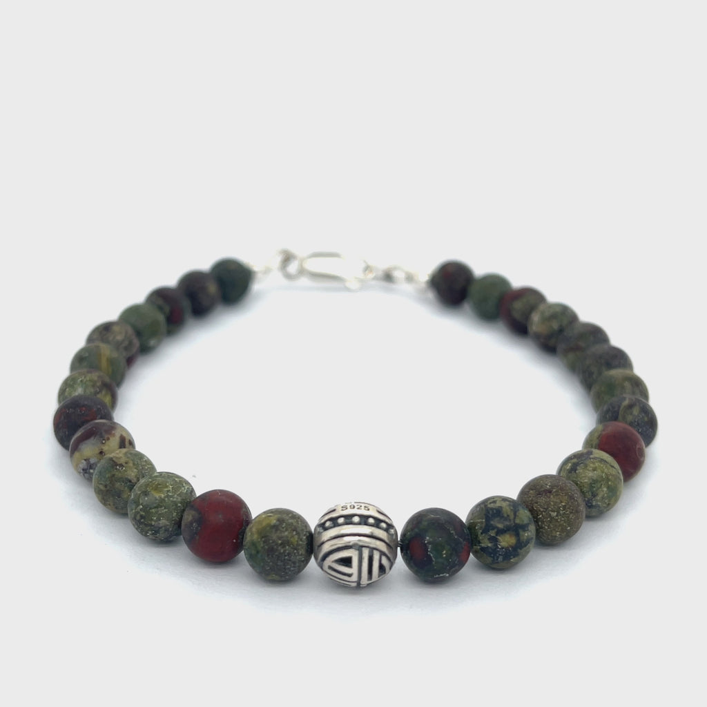 Dragon Blood Jasper gemstone beaded bracelet with sterling silver pattern bead and a lobster claw clasp showing red and green natural patterns  on a white background, front view.  video