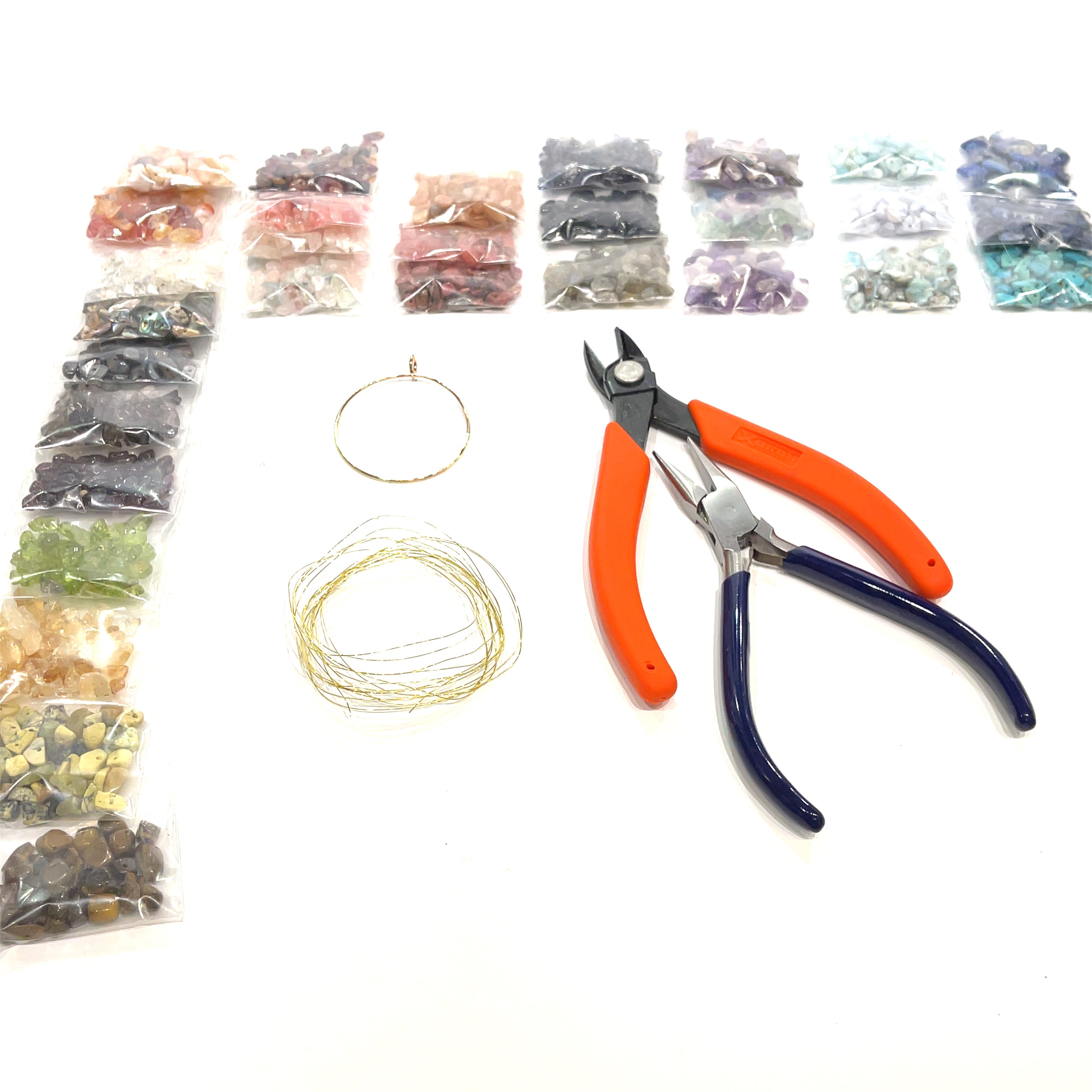 a layout of the tools, brass wire, and a large selection of gemstone chip bags, on a white background, front view. 
