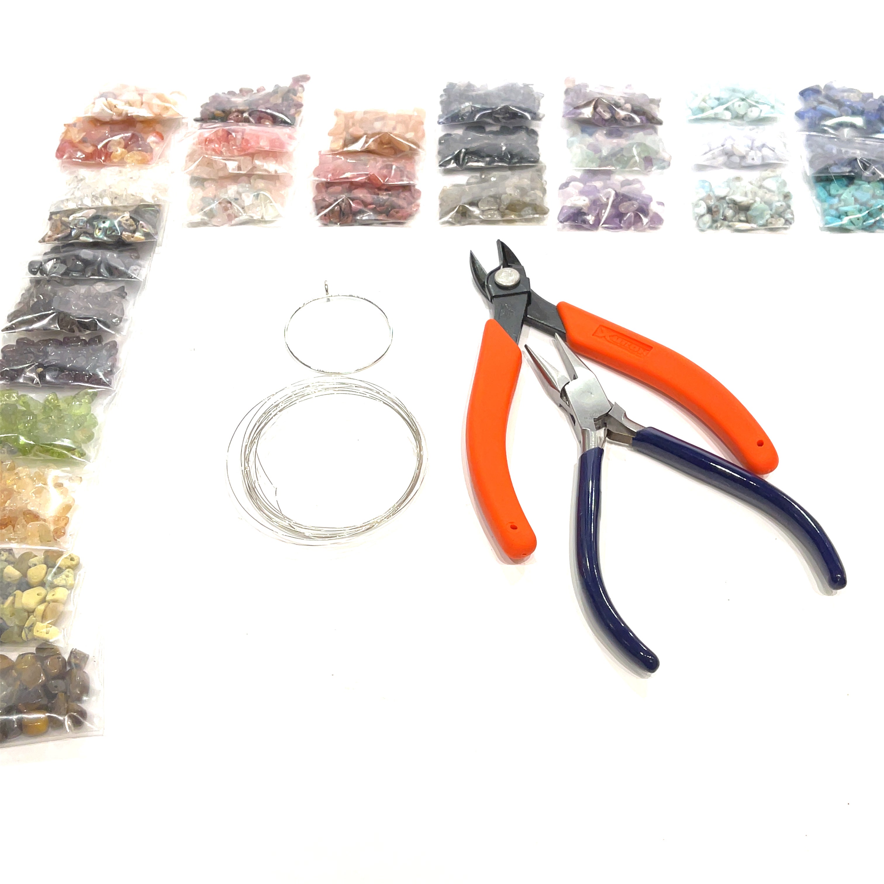 a layout of the tools, sterling silver wire, and a large selection of gemstone chip bags, on a white background, front view. 