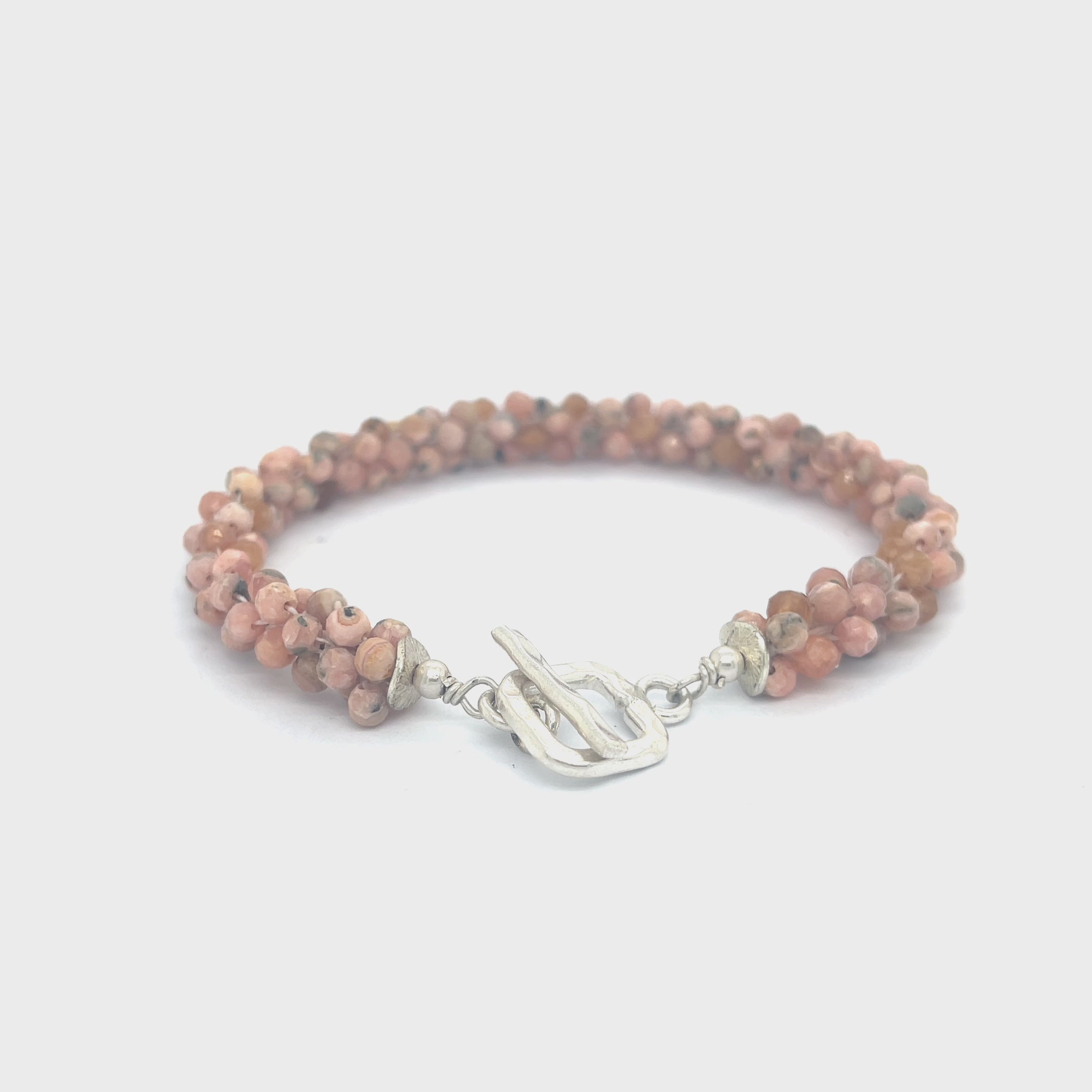 Hand-crocheted Rhodochrosite gemstone bracelet with sterling silver  toggle clasp on a white background front center overview. video