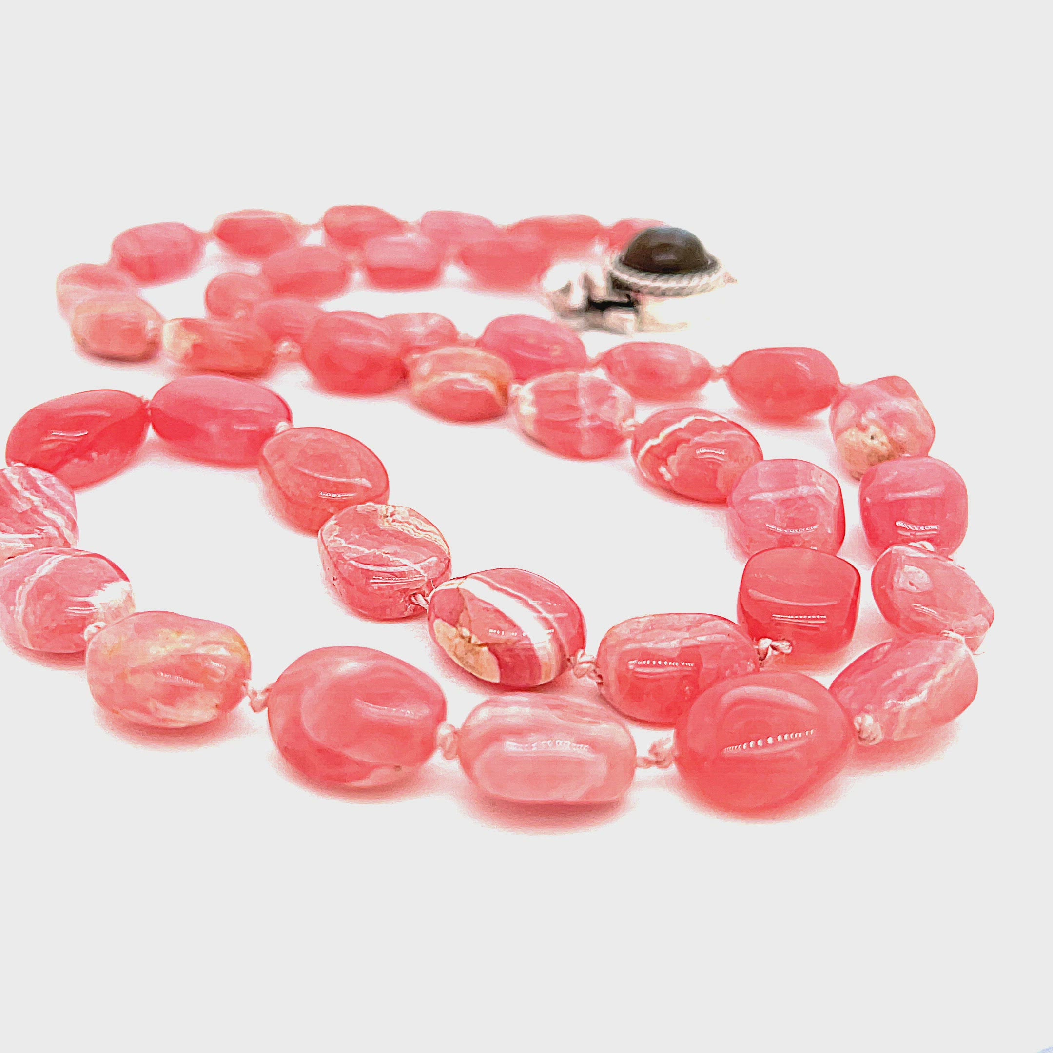 A Rhodochrosite gemstone knotted necklace with a sterling silver Labradorite gemstone box clasp, on a white background, front, long overview. video