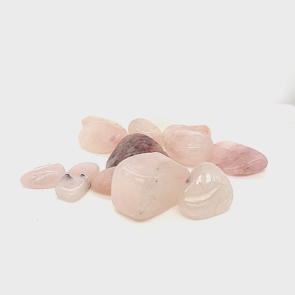 A collection of xs tumbled Petalite gemstones with a pink hue, displayed on a white background, front overview. video