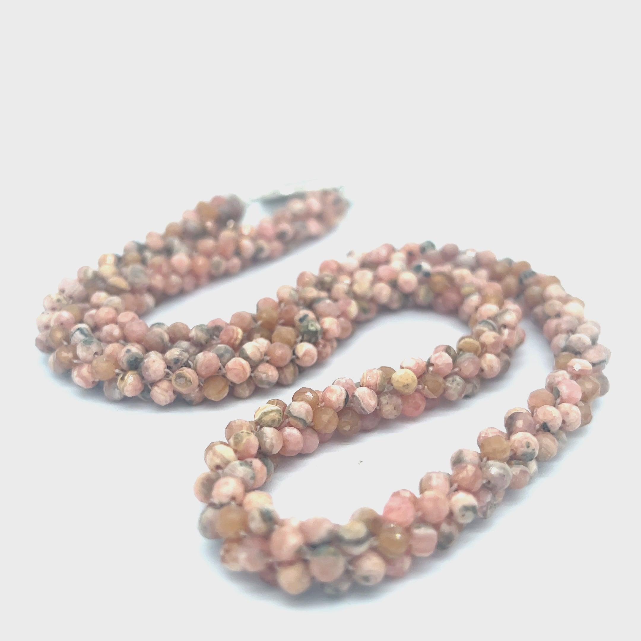 Hand-crocheted Rhodochrosite gemstone necklace with sterling silver toggle and Blue Topaz accent – Hidden Jewel of the South End on a white background, a long center close up overview. video