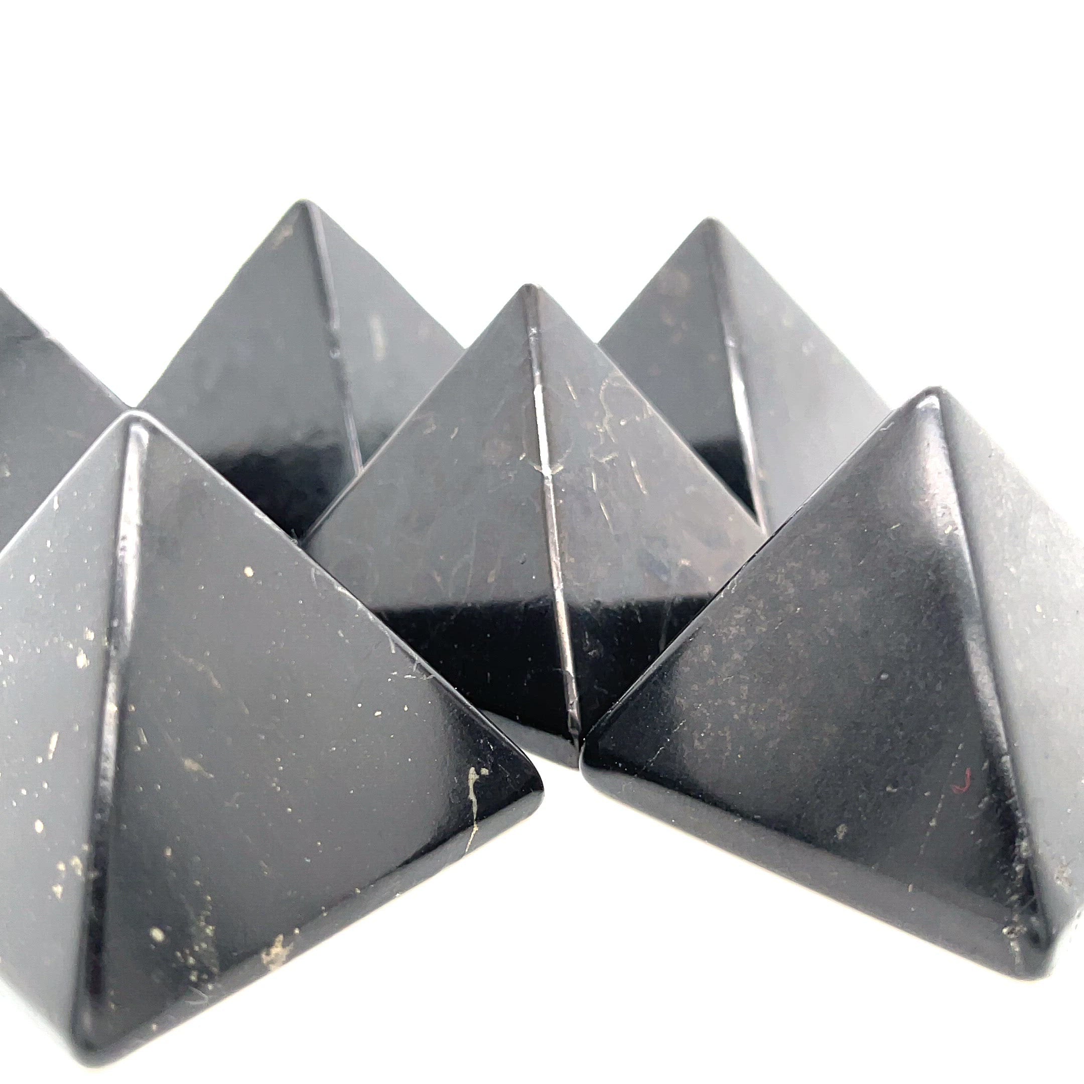 A group Black shungite pyramid for EMF protection and electromagnetic shielding on a white background, front view video.