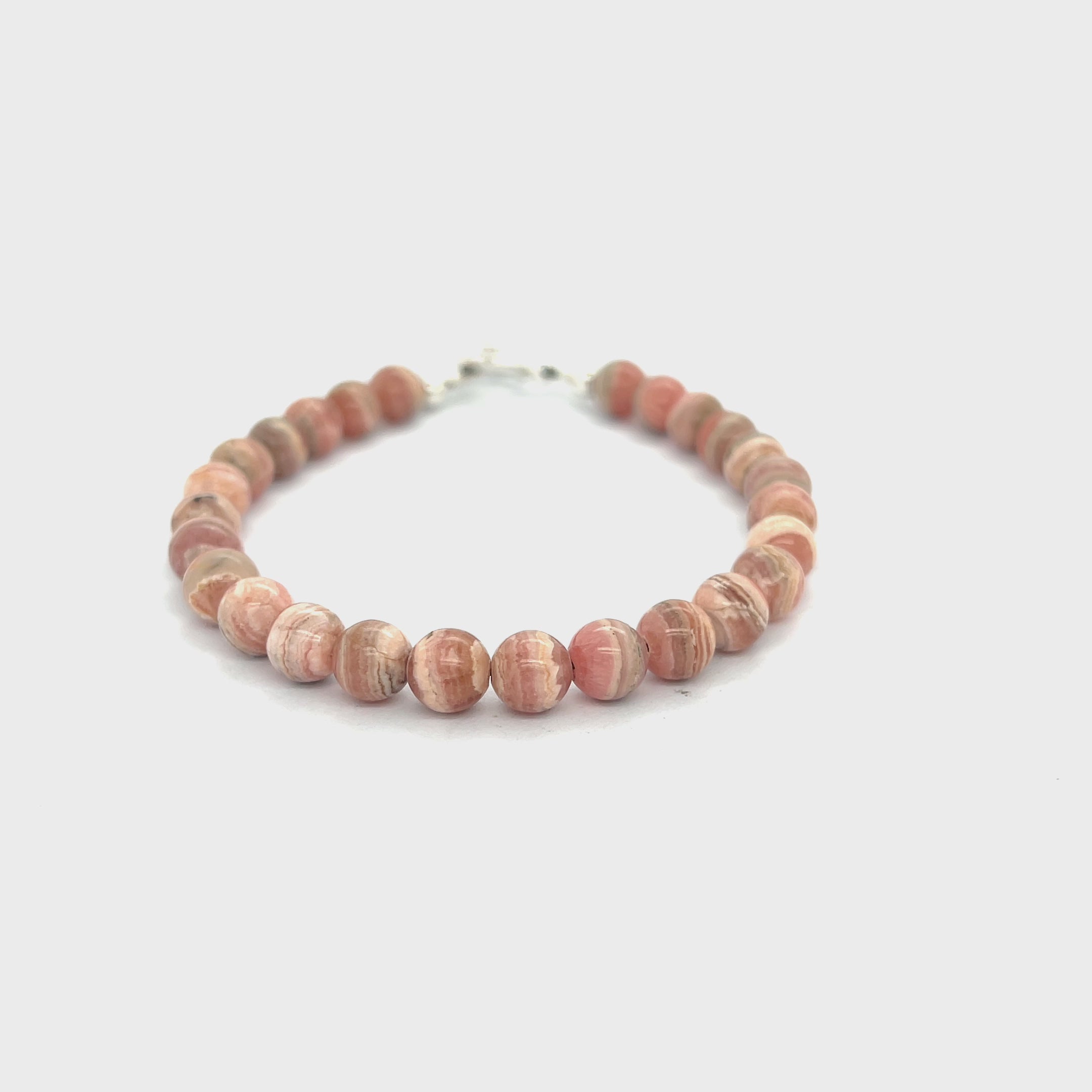 A Rhodochrosite Gemstone 6mm smooth round beaded bracelet with a sterling silver toggle, on a white background, front overview. video