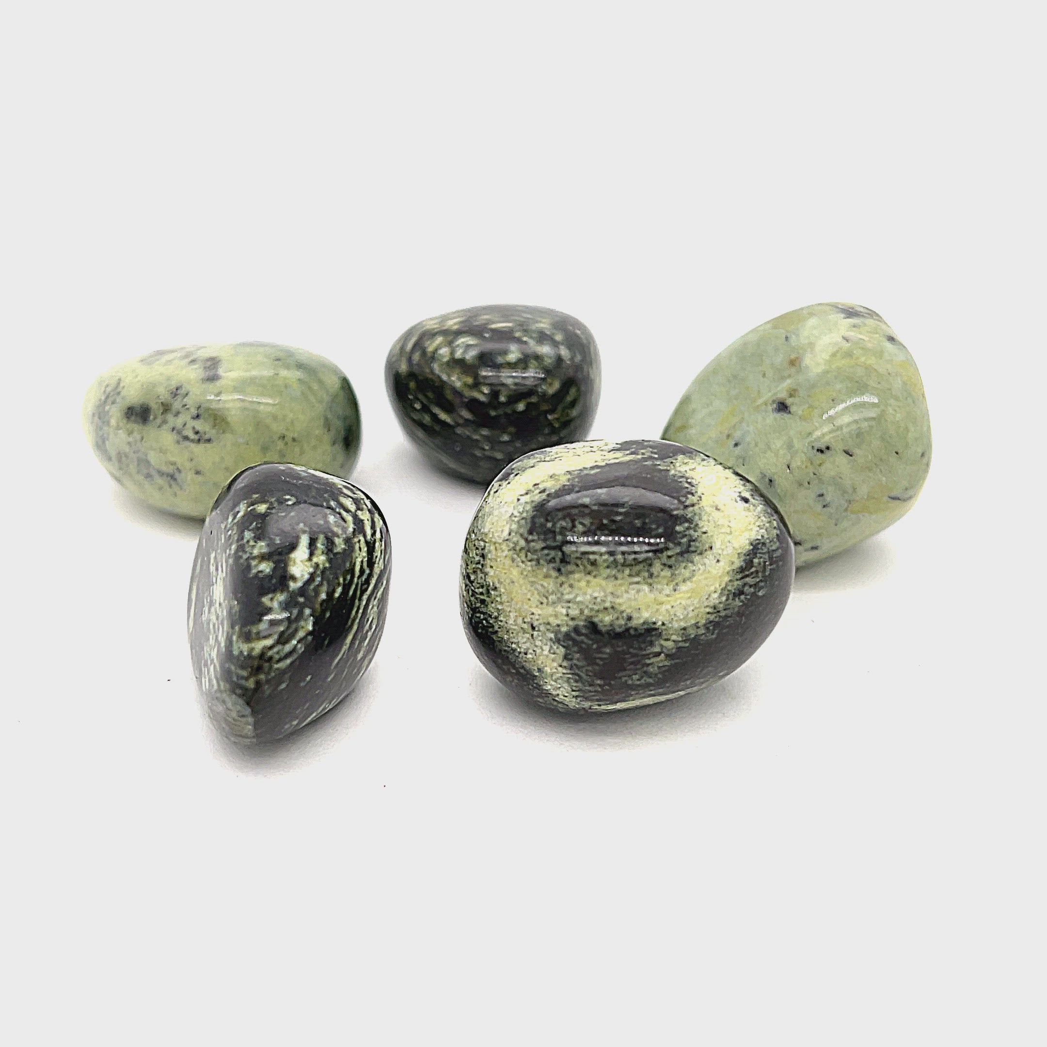 A collection of tumbled Chytha gemstones with a greenish hue, displayed on a white background, front overview. video