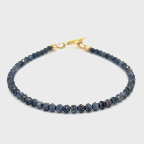 Close-up of 3mm faceted blue sapphires strung on steel cord showing vivid color and sparkle on a white background front overview video